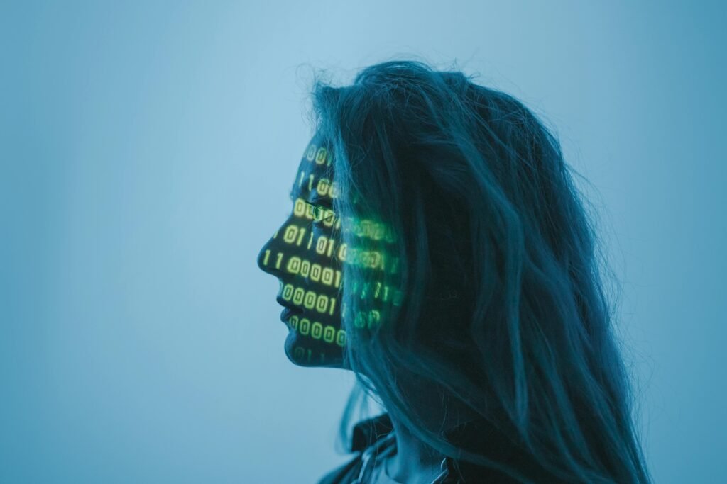 Zijaanzicht van een vrouw met binaire code geprojecteerd op haar gezicht, tegen een blauwe achtergrond.